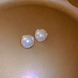 Elegant French retro style round pearl stud earrings with gold trim on golden tray texture