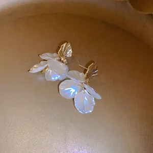 Detail of French vintage shell earrings with white iridescent petals and gold finish