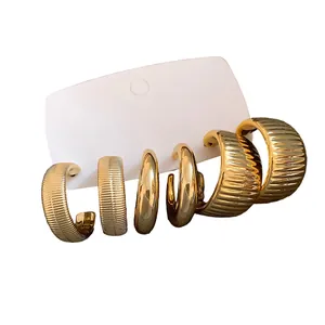 Set mit unregelmäßigen goldenen Creolen, strukturiert und glatt, im Vintage-Stil auf Karte