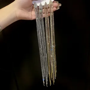 Close-up of sparkling long tassel earrings featuring rhinestones in silver and gold finish