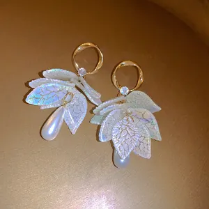 Close-up of elegant French retro earrings with iridescent leaves and teardrop pearls.