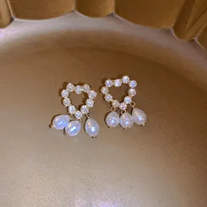 Close-up detail of vintage heart earrings with sparkling zircons and dangling white pearls