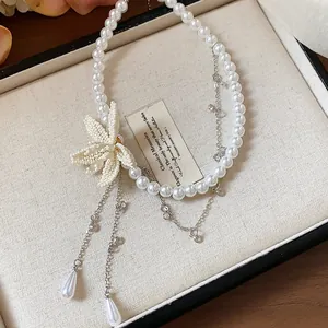Close-up detail of beaded flower and teardrop pearl charms on a white beaded necklace
