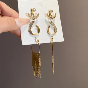 Detailaufnahme eines goldenen geometrischen Ohrring-Sets mit Quasten und Kristallen