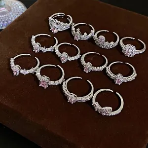 Elegant silver-colored adjustable rings with pink zircons on brown display stand