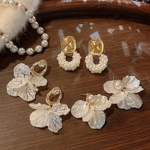 Exquisite detail view of French retro shell petal and pearl earrings on a wooden tray