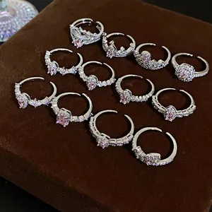 Close-up of various silver-colored rings with pink zircons on a brown velvet base.
