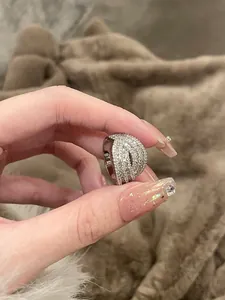Detailed view of a shiny multi-layer zircon encrusted geometric ring held by hand