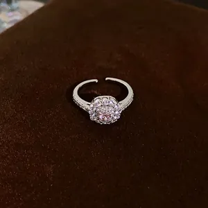 Detail shot of an adjustable silver ring with a pink round halo cubic zirconia stone.