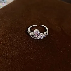 Macro detail of a silver crown-shaped ring with a pink zircon and white crystals