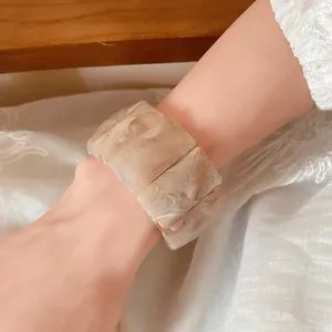 Close-up detail of cream marbled acrylic rectangular links on an elastic bracelet