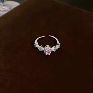 Close-up detail of silver-finish ring featuring a central pink zircon and side accents