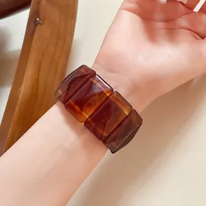 Close-up of retro acrylic rectangular bracelet with brown marble texture on wrist.