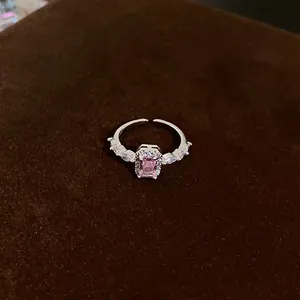 Detail view of a silver ring with a sparkling pink rectangular stone and clear zircons.