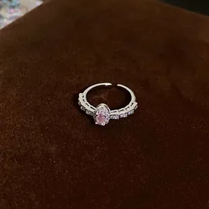 Close-up detail of a sparkling silver ring with a pink oval zircon on dark velvet