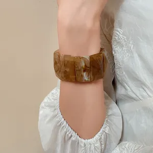 Detailed view of a vintage marbled acrylic rectangular stretch bracelet worn on a wrist.