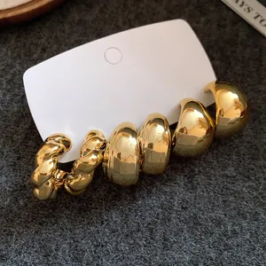 Nahaufnahme von goldenen unregelmäßigen Wassertropfen- und Creolen-Ohrringen auf Displaykarte