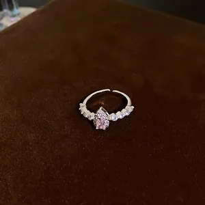 Macro view of a silver ring featuring a pear-shaped pink zircon on brown velvet