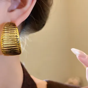 Detailaufnahme eines goldenen, gerippten Creolen-Ohrrings im Vintage-Stil am Ohr