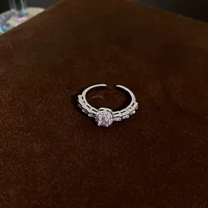 Close-up of a silver ring with a square pink zircon and sparkling accent stones.