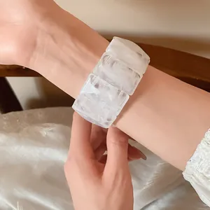 Detail view of a white marbled acrylic rectangular bead elastic bracelet on a wrist