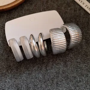Detailansicht von drei Paar silbernen geometrischen Ohrringen mit glatten Oberflächen