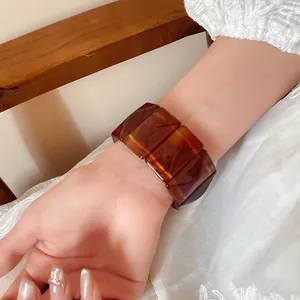 Close-up of a wide tortoiseshell acrylic elastic bracelet worn on a woman's wrist.
