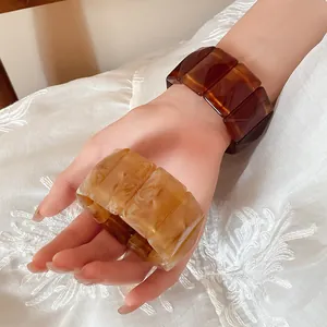 Detail shot of retro chunky amber marbled acrylic stretch bracelets worn on wrist