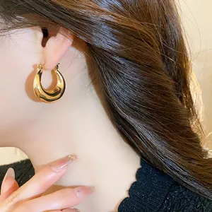 Detailaufnahme eines klobigen 18K vergoldeten Creolen am Model