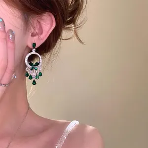 Detailed view of vintage green butterfly tassel earrings worn on ear with soft lighting