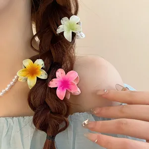 Vue rapprochée de trois pinces à cheveux en forme de fleur colorée dans une tresse.