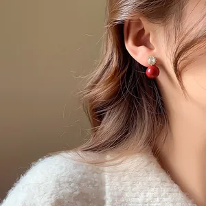 Boucles d'oreilles élégantes en perles rouges et fleur de zircon sur un mannequin.