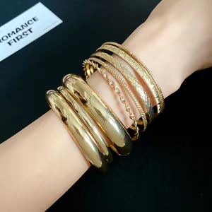Detailed view of layered gold metallic bangles with geometric textures on wrist