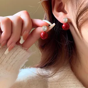 Gros plan détaillé de boucles d'oreilles perles rouges avec fleur en zircon étincelante.