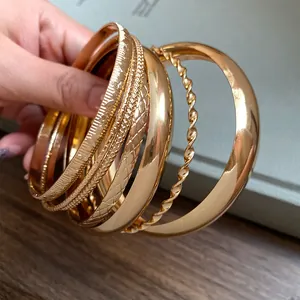 Detailed view of gold metal bangles featuring geometric textures and twisted designs.