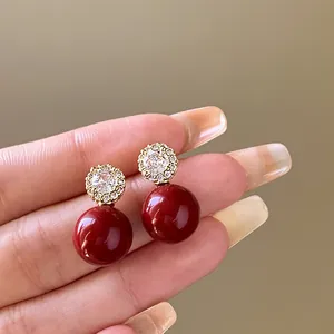 Vue détaillée de près d'élégantes boucles d'oreilles fleur en zircon et perles rouge foncé