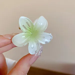 Vue détaillée d'une mini pince à cheveux en forme de fleur verte et blanche en résine