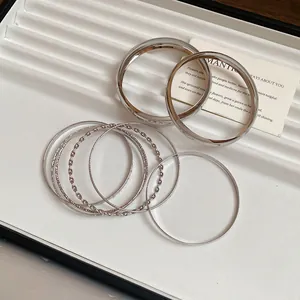 Detail view of silver metallic bangles with smooth and twisted textures.
