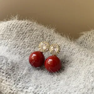 Détail des boucles d'oreilles en perle rouge vintage avec un motif fleur en zircone