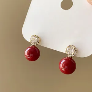 Détail macro de boucles d'oreilles perles rouges avec des clous en fleurs de zircone