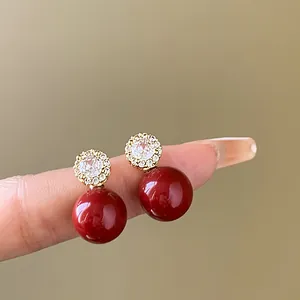 Détail de boucles d'oreilles perles rouges élégantes avec un motif floral en zircon.