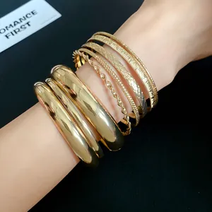 Detailed view of layered gold-tone geometric textured bracelets on wrist