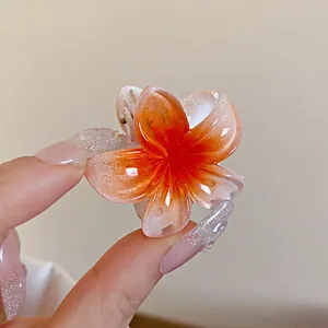 Gros plan d'une élégante mini pince à cheveux fleurie dégradé orange avec paillettes
