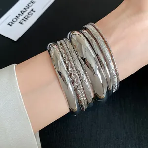 Detailed macro shot of various textured silver metal bangles worn on a female wrist
