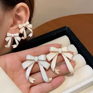 Elegant cream white enamel bowknot stud earrings with gold edges and silver needles