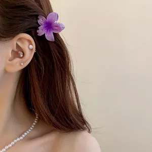 Gros plan d'une mini pince à cheveux fleur violette sur des cheveux bruns