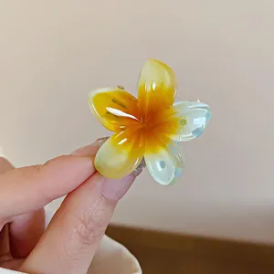 Gros plan d'une petite pince à cheveux en forme de fleur jaune translucide en résine