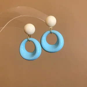 Dettaglio di orecchini pendenti circolari in acrilico azzurro e crema