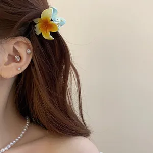 Vue rapprochée d'une pince à cheveux fleurie minimaliste portée sur des cheveux bruns.