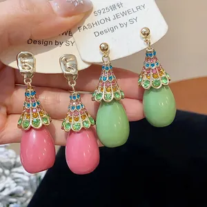 Close-up of vintage resin waterdrop earrings with multi-colored rhinestones and silver needles.